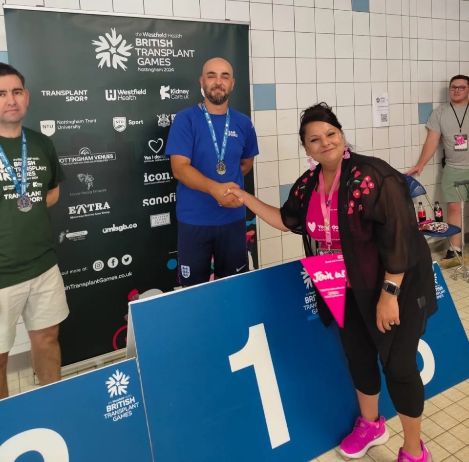Nick Barnard shaking hands with a woman next to a podium at the British Transplant Games.