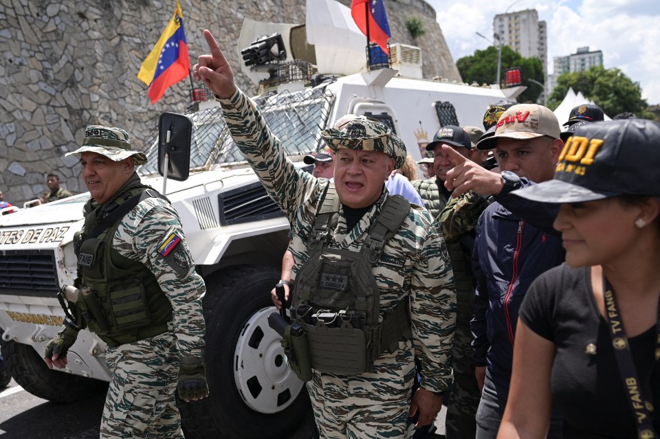 Venezuela's Interior Minister Diosdado Cabello in military uniform with Venezuelan flags on a military vehicle.