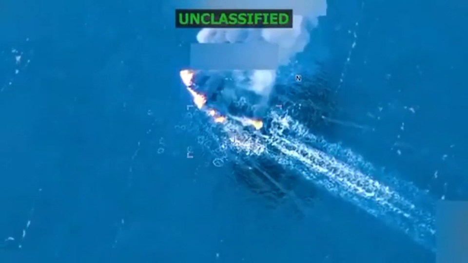 Aerial view of a boat on fire in the ocean, with a label "UNCLASSIFIED" at the top.