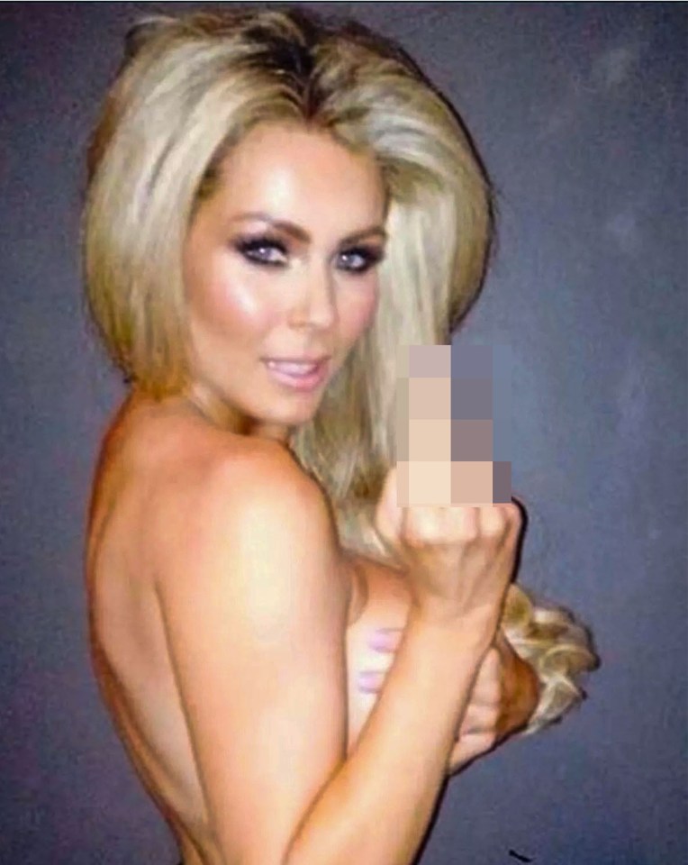 Woman with blonde hair posing, partially nude, making a rude hand gesture.