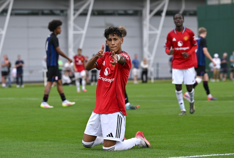 Manchester United's JJ Gabriel kneels on the field celebrating a goal.