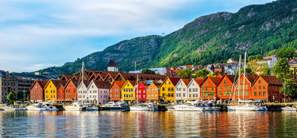 Colorful buildings of Bryggen Hanseatic wharf in Bergen, Norway, with boats docked in the harbor.
