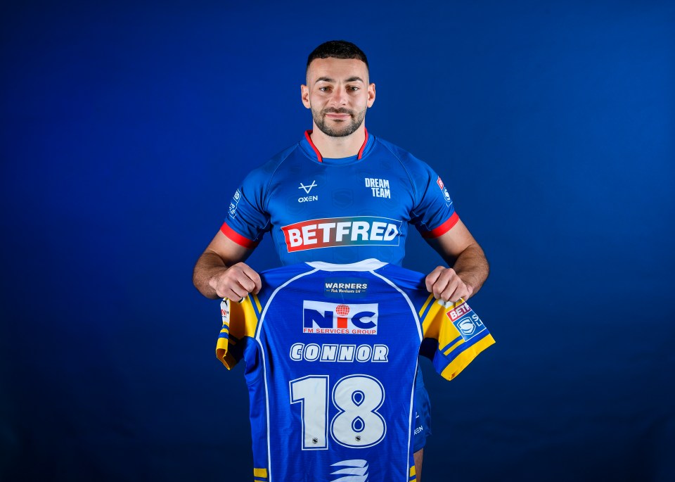 Connor holding up a jersey with "CONNOR 18" on the back.