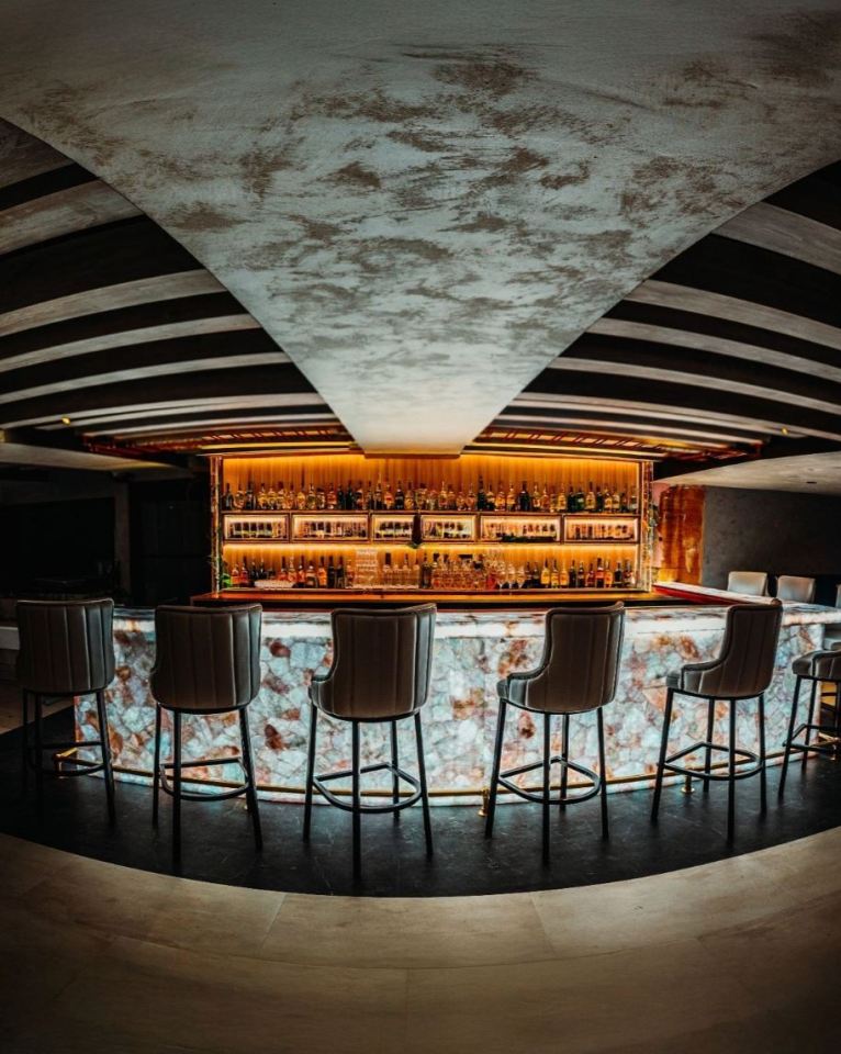 Interior of the SDK restaurant and bar, featuring a glowing bar with bottles and stools.