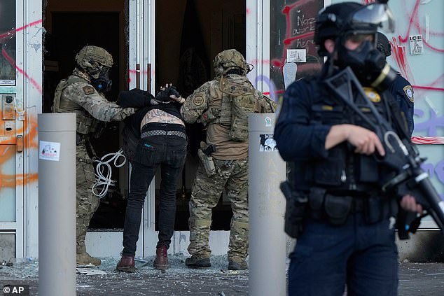 Pictured: Customs and Border Protection agents detain a man protesting outside the ICE building in Portland on June 14