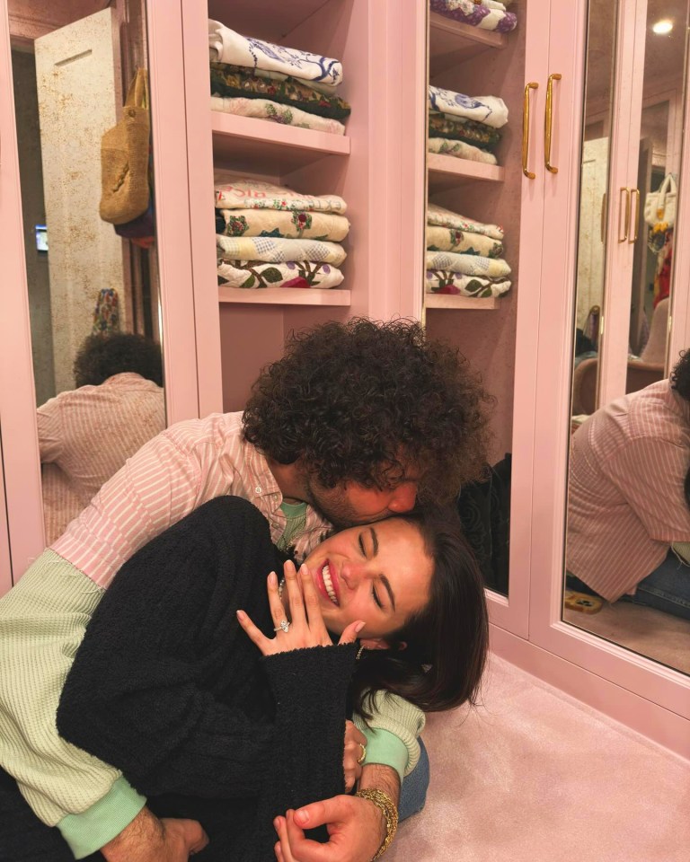 Benny Blanco kissing Selena Gomez on the forehead while she smiles and shows her engagement ring.
