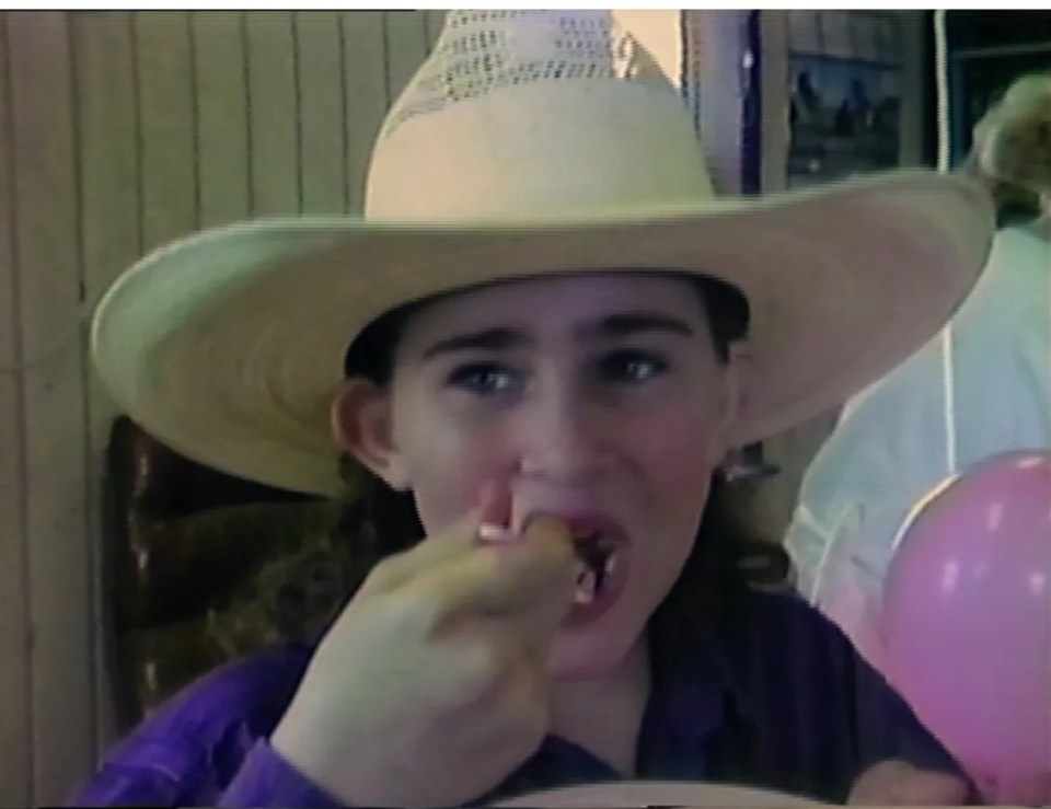 Amy Ayers, 13, wearing a white cowboy hat, eating from a plate with a fork.