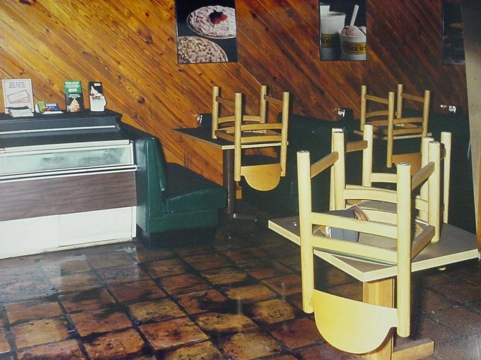 Interior of the I Can't Believe It's Yogurt shop in Austin, with chairs stacked on tables and a display case.