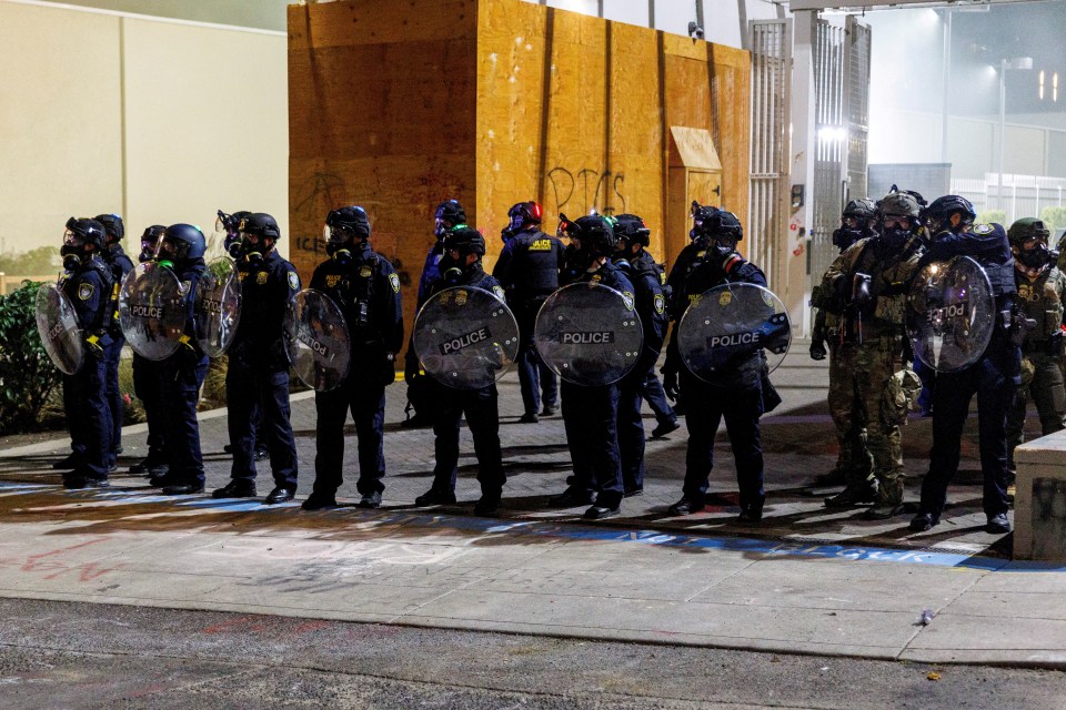 ICE agents stand guard in riot gear during a protest in Portland, Oregon.