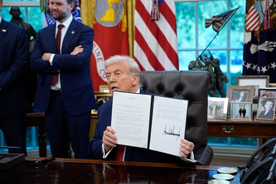 President Donald Trump speaks as he holds up executive orders signed in the Oval Office.