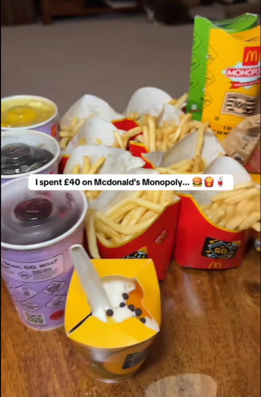A table covered with McDonald's food and drinks, including a large quantity of french fries, multiple drinks, and a sundae, with a "McDonald's Monopoly" wrapper visible.