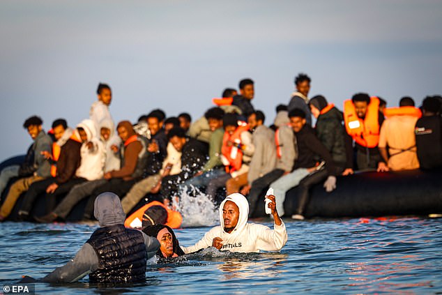 Migrants board an inflatable boat during an attempt to cross the English Channel, off the beach of Gravelines, northern France, 27 September 2025
