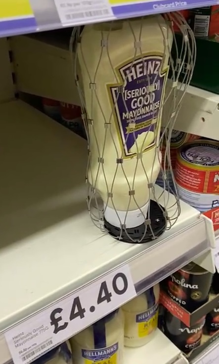 A bottle of Heinz mayonnaise on a supermarket shelf with a security tag around it, priced at £4.40.