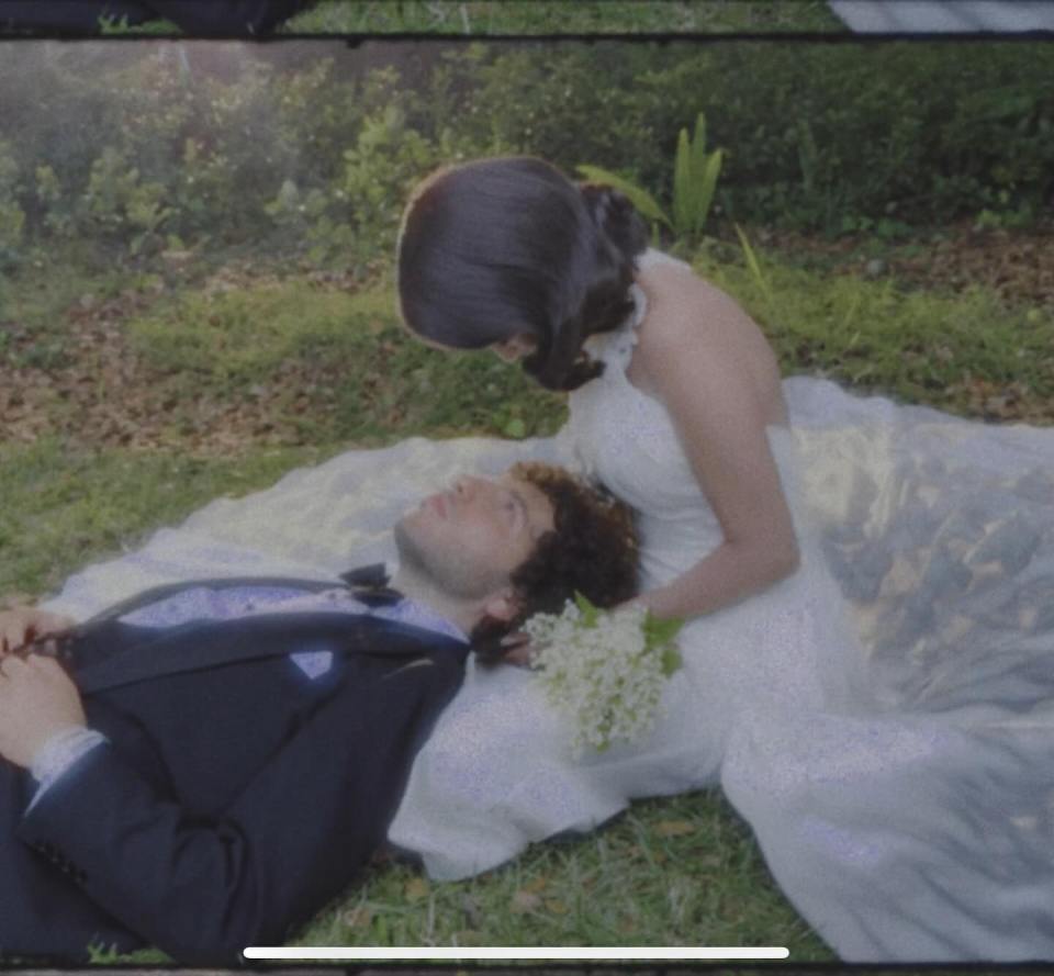 Selena Gomez looking down at Benny Blanco lying in her lap at their wedding.