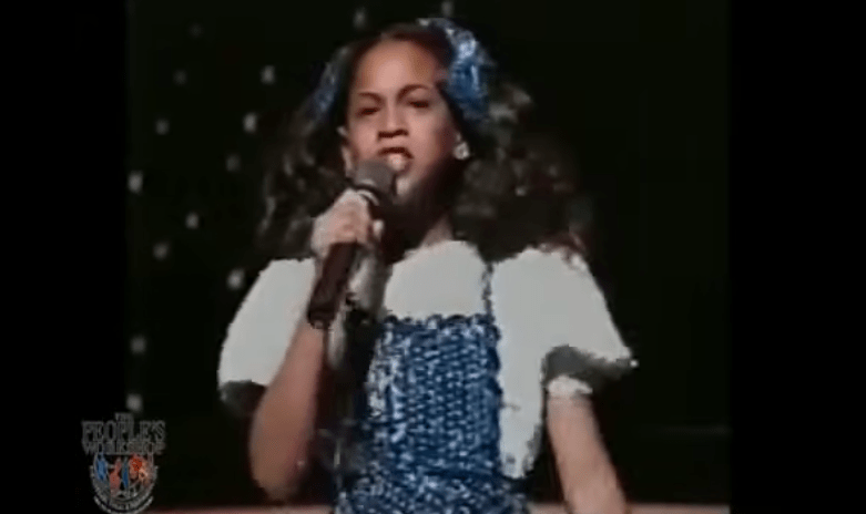 A young Beyoncé singing into a microphone.