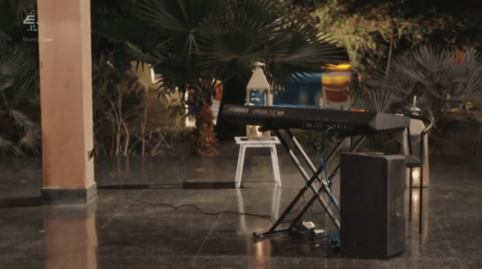 A Yamaha MOXF keyboard on a stand, with a speaker and lights.