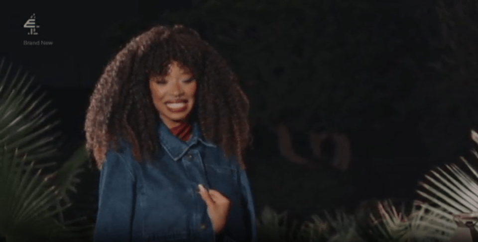 A woman in a denim jacket is smiling widely.