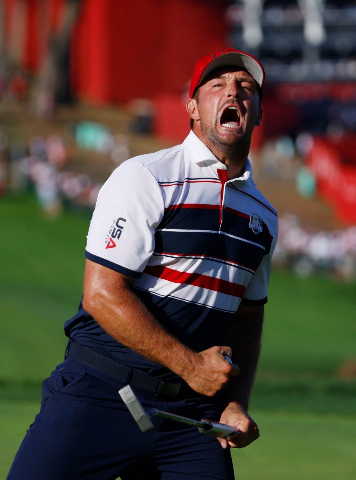 Bryson DeChambeau, wearing a red hat and USA Ryder Cup shirt, yells on the 18th hole.
