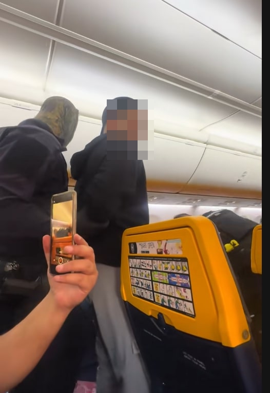 A person records two blurred passengers on a Ryanair flight.
