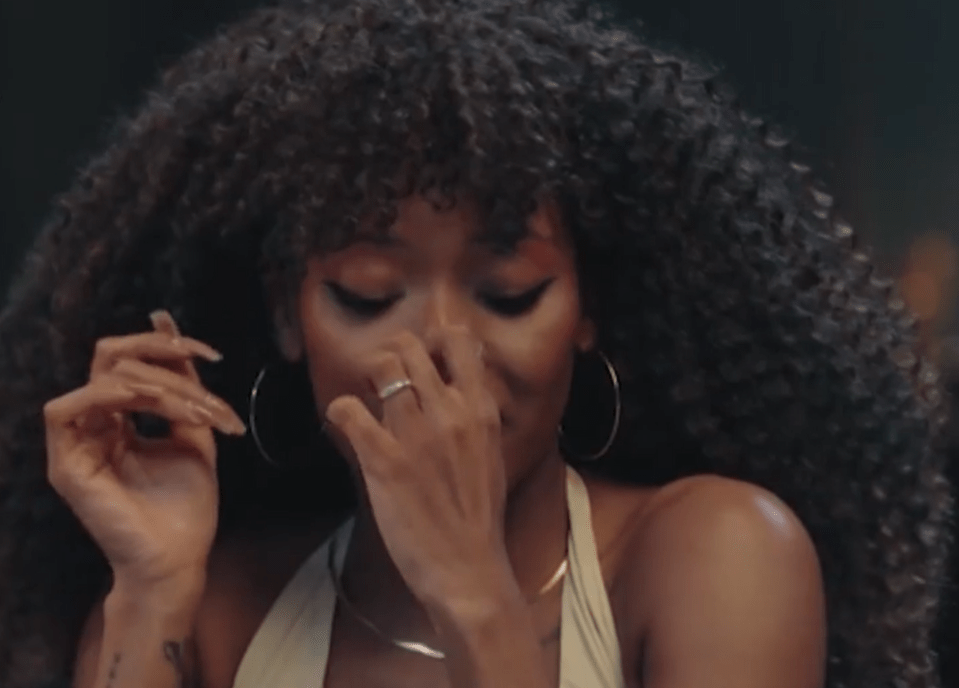 A woman with curly hair covers her nose with her hand.