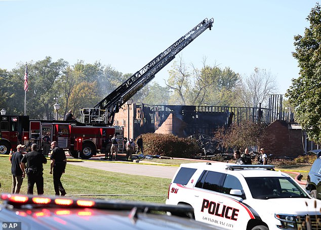 A firetruck ladder is seen over the burnt building following the fire and shooting Sunday