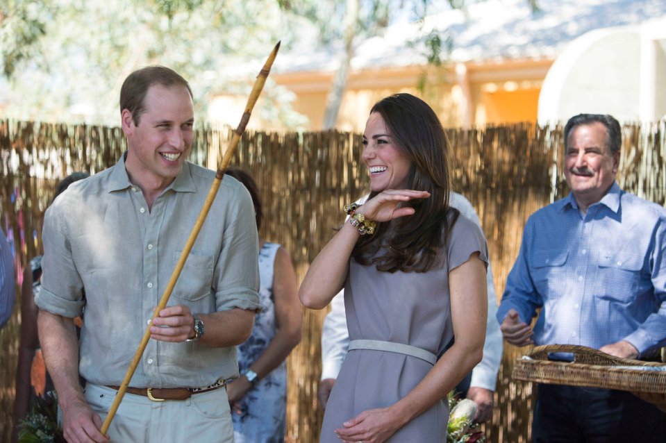 Prince William holding a spear, laughing with Kate Middleton and a man in a blue shirt.