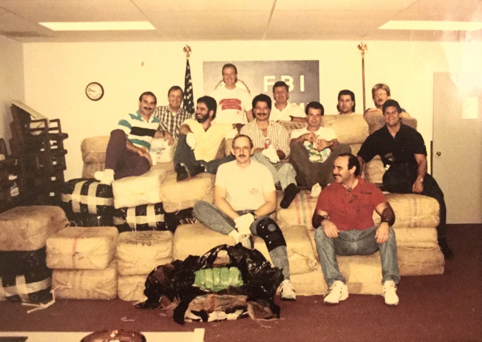 Men posing with bales of illegal narcotics in front of an FBI logo.