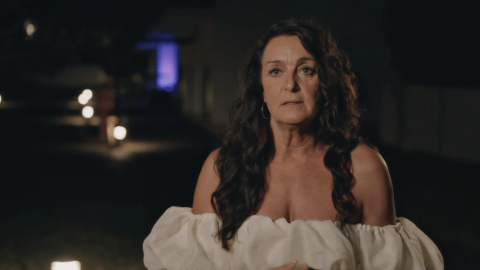 A woman with dark hair wearing an off-the-shoulder white top.