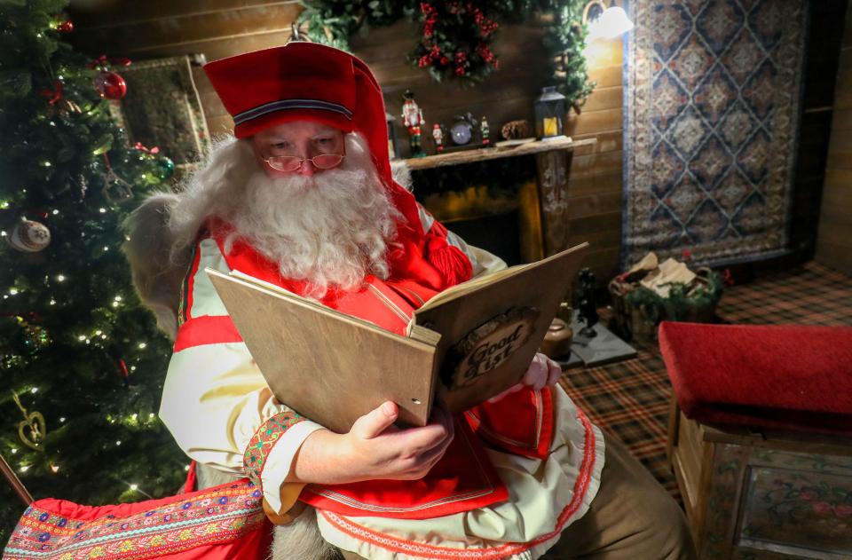Father Christmas reads his 'Good List' inside a woodland cabin.