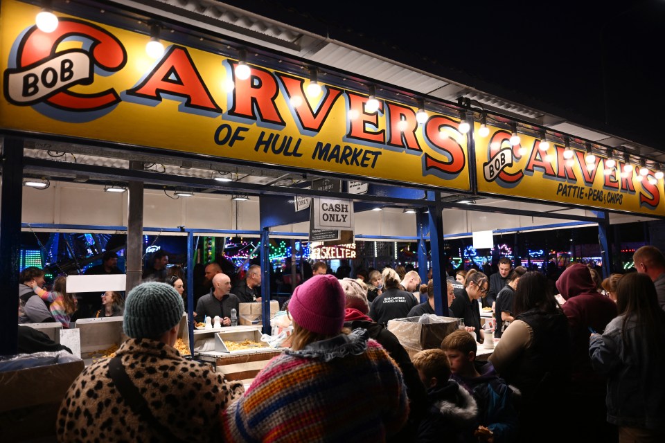 People gather at "Bob Carver's of Hull Market" stall for "Pattie, Peas & Chips" at Hull Fair.
