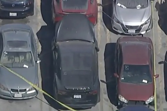 Aerial view of an impounded black Tesla surrounded by yellow police tape and other cars.