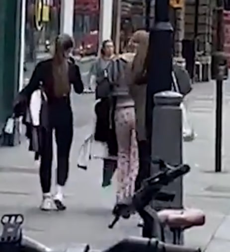 A group of people carrying armfuls of clothes out of an H&M store.