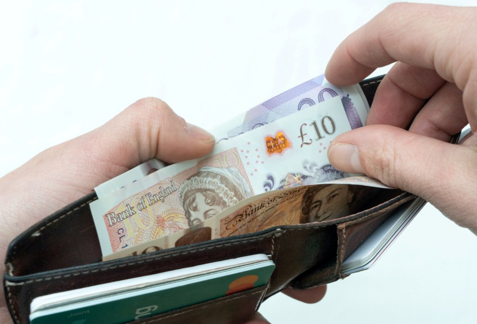 Hands putting British pounds into a wallet.