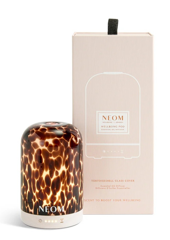 Neom wellbeing pod essential oil diffuser with a tortoiseshell glass cover and its packaging.