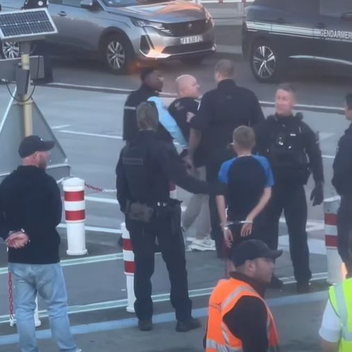 Police officers arresting a man on an airport tarmac.