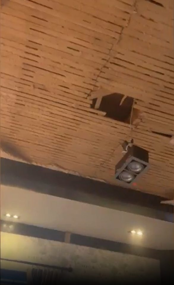 A collapsed ceiling revealing wooden laths and a hanging speaker.