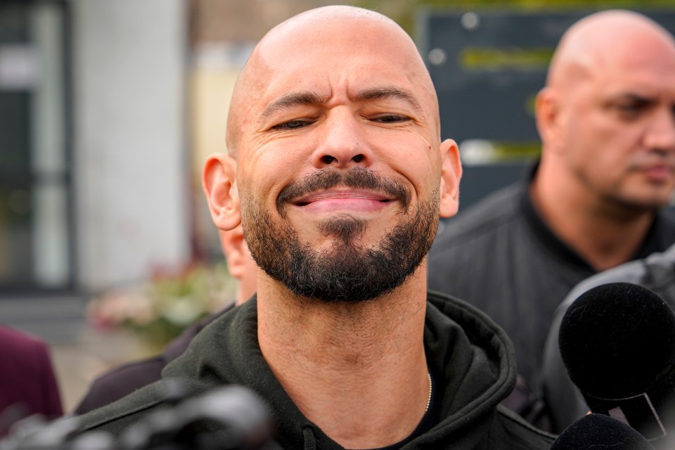 Andrew Tate reacting to media questions while at a police station.