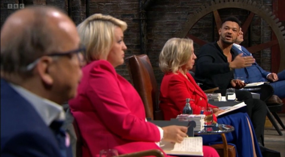 Four businesspeople, including two women and two men, sit facing right in the Dragons' Den studio.