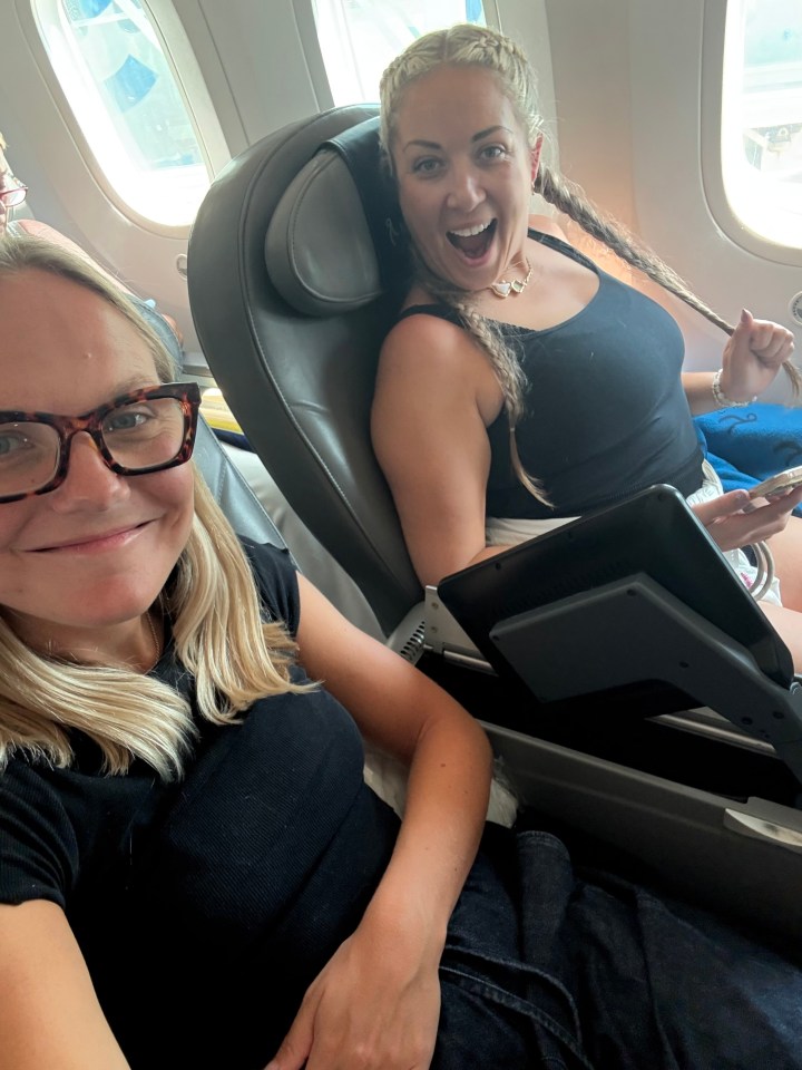Two women smiling on an airplane.