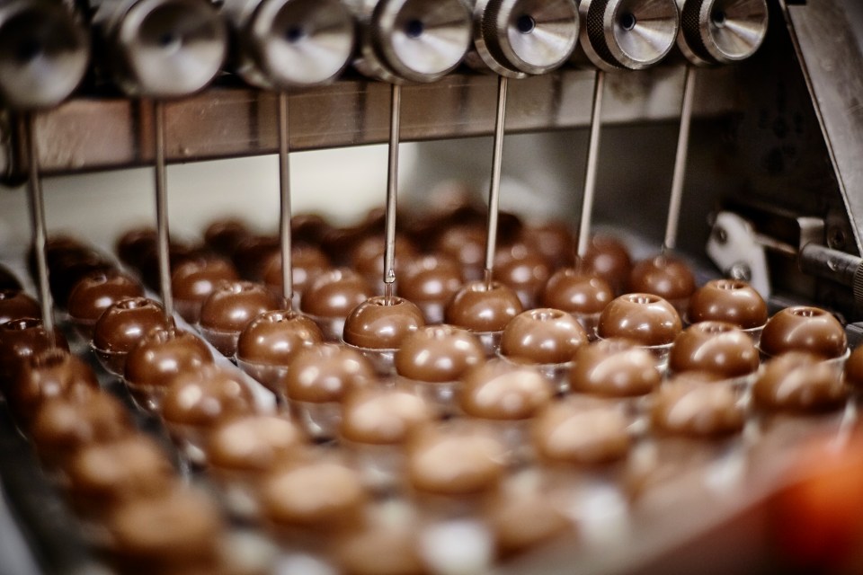 Machine filling confectionery with chocolate liquid.