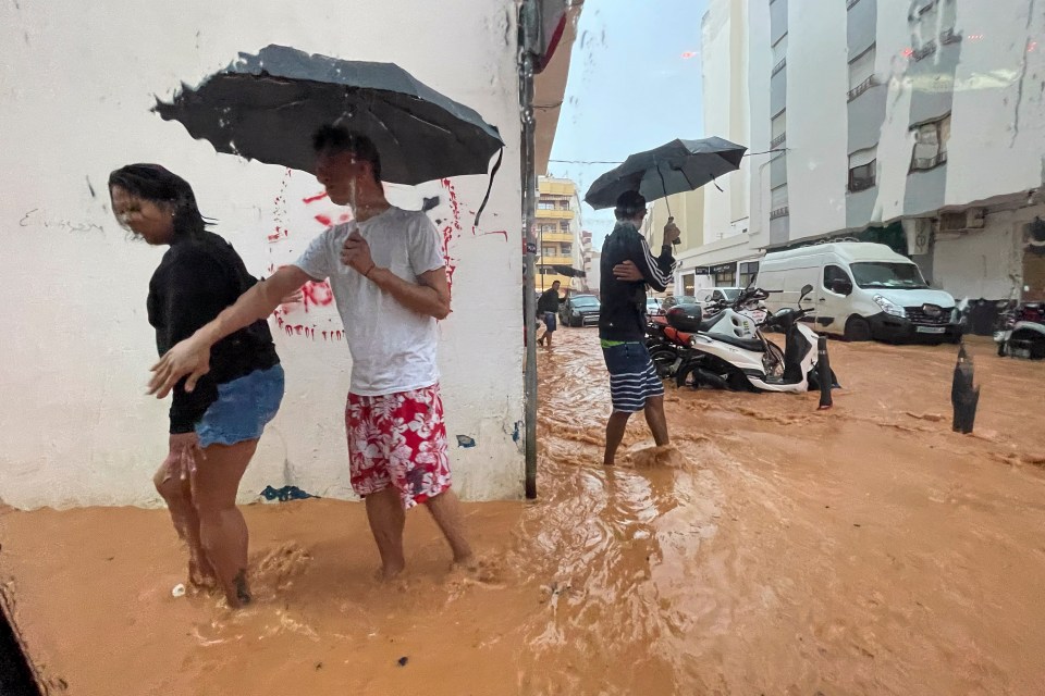 People walking along flooded streets in Ibiza, Spain.