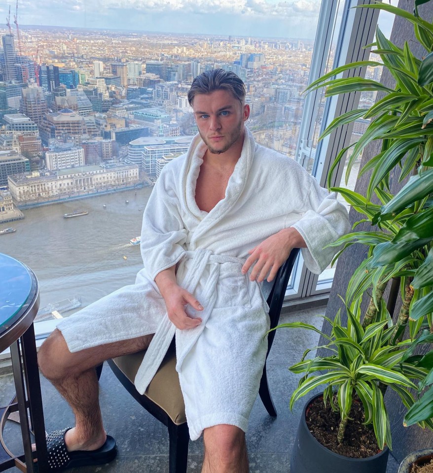 Ed Matthews, a TikTok user, in a white bathrobe sitting in a high-rise with a city view.