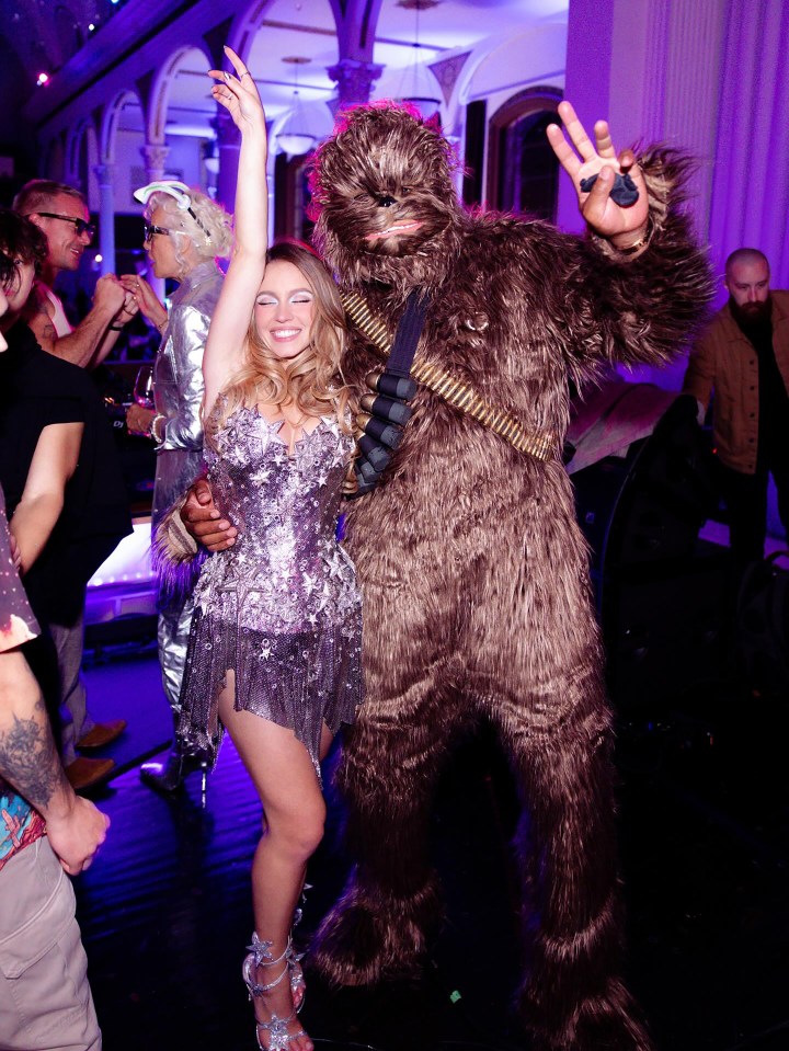 Sydney Sweeney in a sparkly star dress dancing next to Chewbacca from Star Wars.