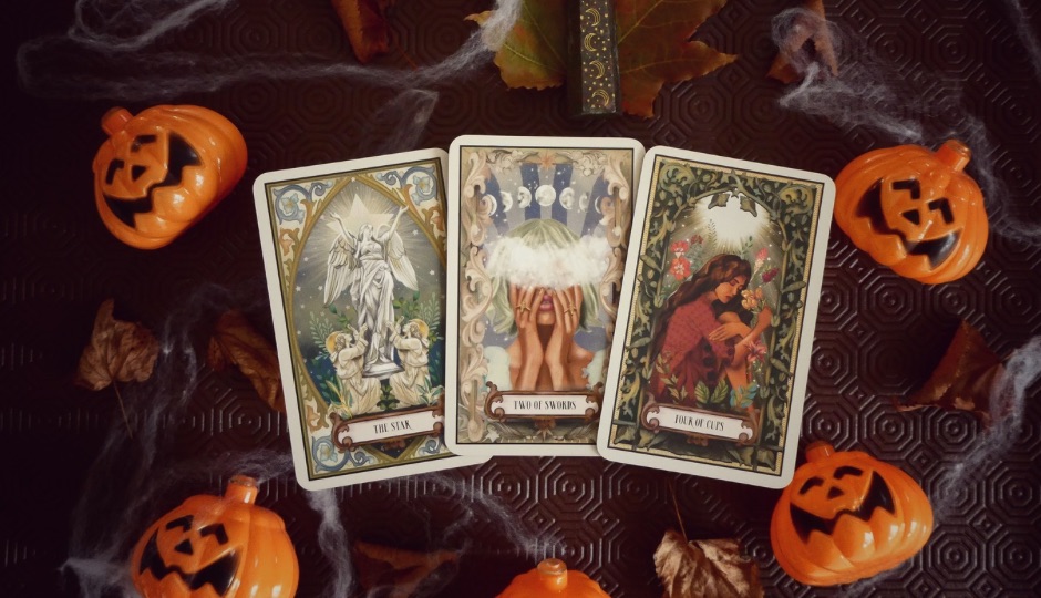 Three tarot cards titled "The Star," "Two of Swords," and "Four of Cups" are surrounded by small orange pumpkins, spiderwebs, and autumn leaves.