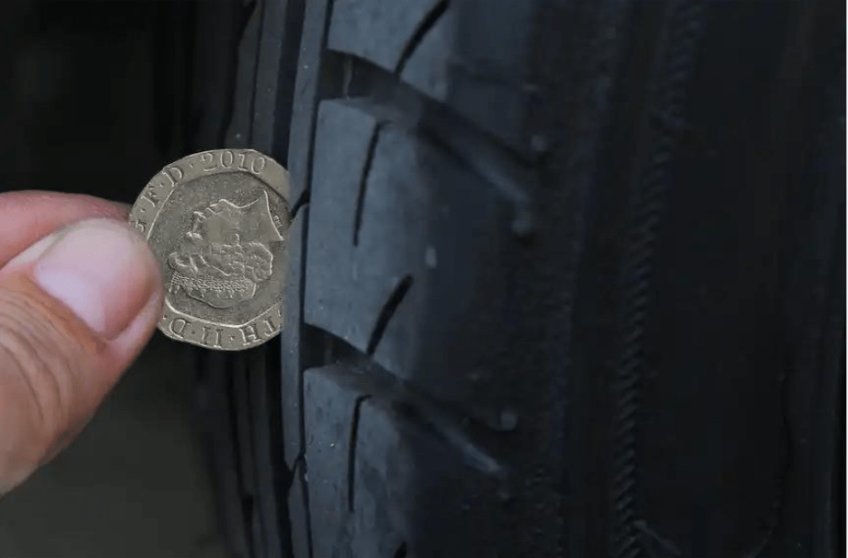 A coin inserted into a tire tread to check tire depth.