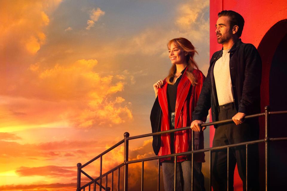 Margot Robbie and Colin Farrell on a balcony overlooking an orange sky.