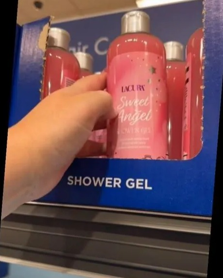 Hand picking up Lacura Sweet Angel shower gel from an Aldi display.