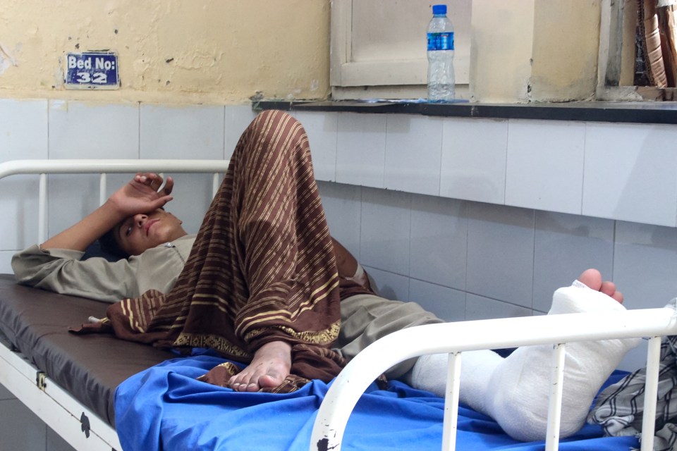 Injured Afghan man in hospital bed with leg in cast.