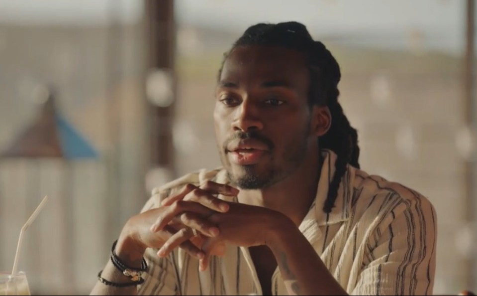 Man with dreadlocks wearing a striped shirt.