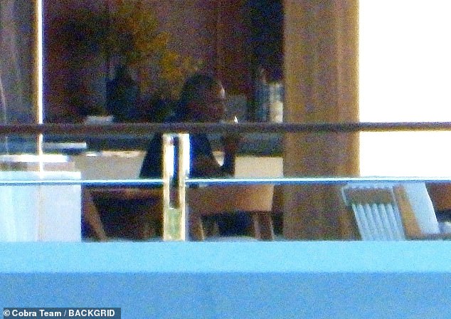 The former president sips from a glass as he sits by himself